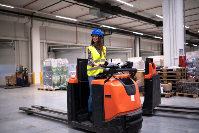 woman using electric pallet trucks for moving pallets in warehouse